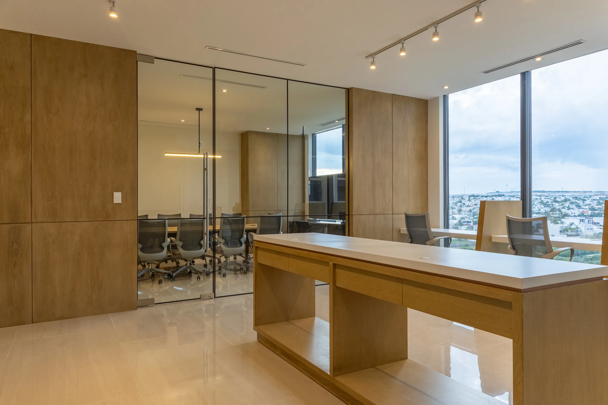 Recepción con escritorio de madera y sala de juntas de cristal al fondo
