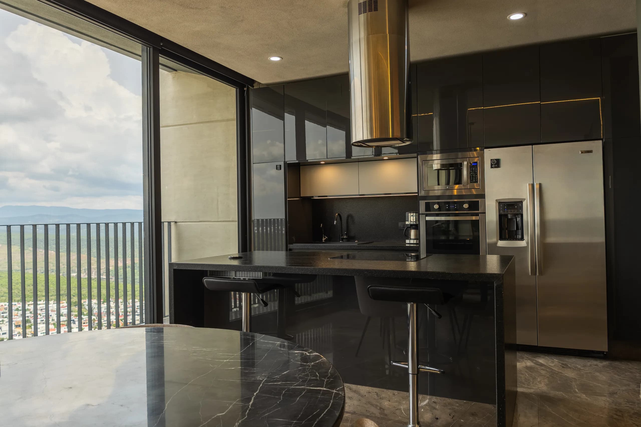 Cocina negra con isla, campana de acero y vista abierta