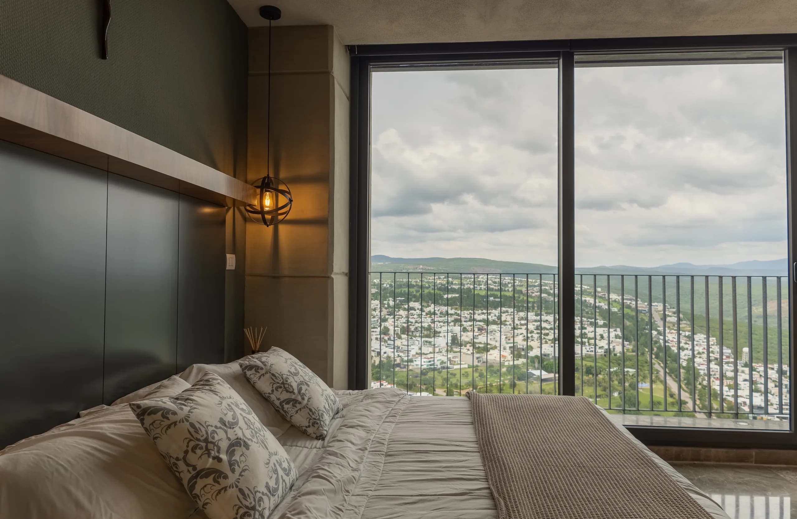 Recámara con cama frente a un ventanal y vista al valle